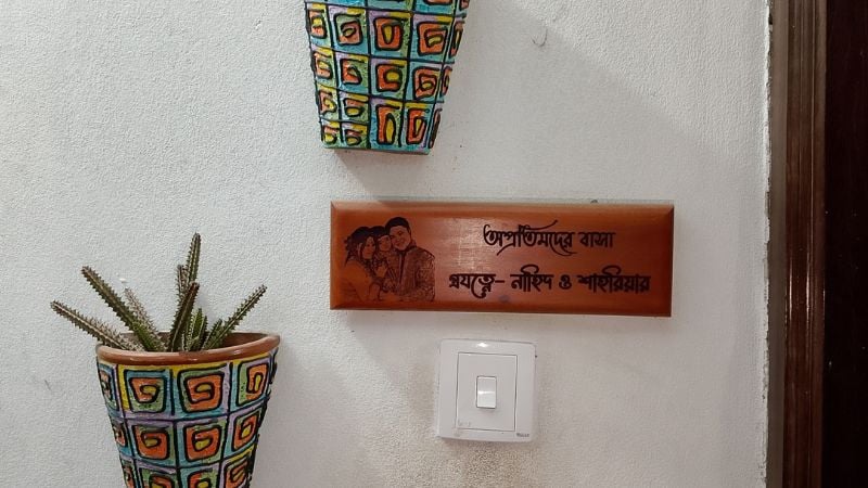 বাড়ির দরজার বাইরে ঝোলানো কাঠের নামফলক। ছবি-সমকাল